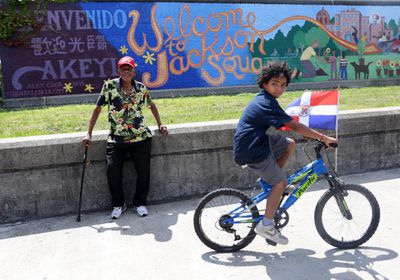 (Boston, MA - 8/13/17) Eliseo, 97, who is originally from the Dominican Republic, watches the Dominican Parade as a boy on a bike rides by on Centre Street in Jamaica Plain, Sunday, August 13, 2017. Staff photo by Angela Rowlings