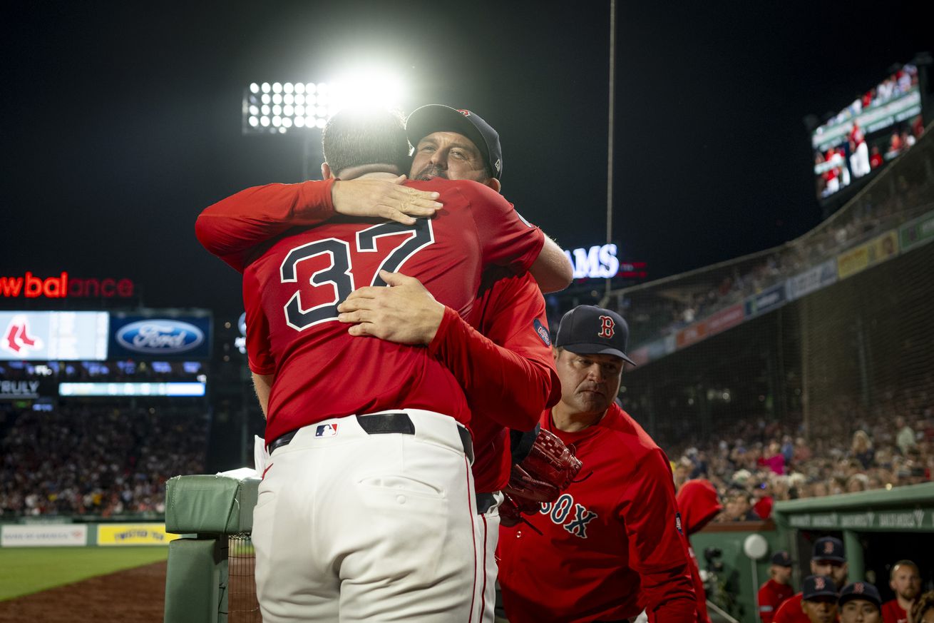 Nick Pivetta #37 of the Boston Red Sox hugs game planning coordinator Jason Varitek, #33, at the top of the dugout steps as he is relieved during the seventh inning of a game against the Tampa Bay Rays in what could’ve been his last appearance in a Red Sox uniform.